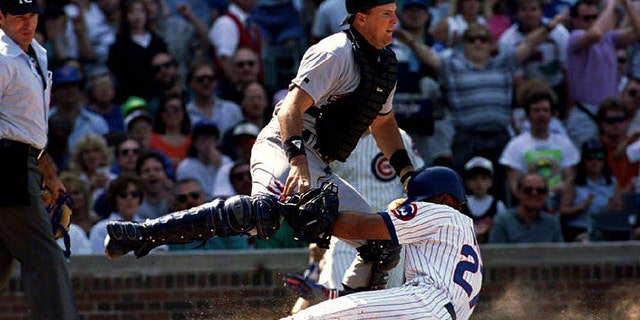 San Diego Padres catcher Dan Walters (C) tries to avoid being run into by sliding Chicago Cub Derrick in May 1993 as he scores in the second inning at Wrigley Field. May scored on a single by Steve Buechele as umpire Angel Hernandez (L) looks on. (Photo credit should read EUGENE GARCIA/AFP via Getty Images)