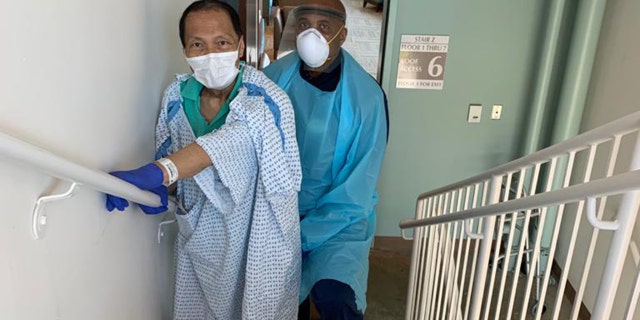 Dr. Bulauitan working with his physical therapist. After extubation he could not lift his arms or legs off the bed. He was told if he could walk up 4 steps, then he could be discharged to his son's home. Within five days, Bulauitan was able to walk!