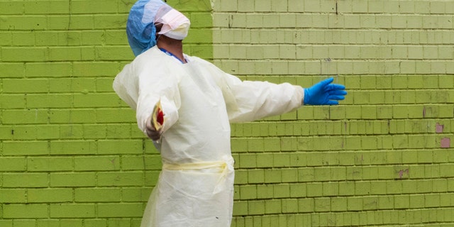 A medic of the Elmhurst Hospital Center medical team reacts after stepping outside of the emergency room, Saturday, April 4, 2020, in the Queens borough of New York.
