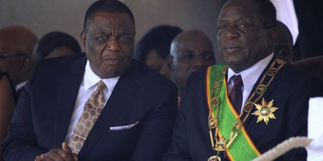 Monday, Aug. 13, 2018, file photo, Zimbabwe's President Emmerson Mnangagwa, right, sits with his Deputy Constantino Chiwenga, left, during a Heroes' Day event in Harare, Zimbabwe. The coronavirus pandemic could narrow one gaping inequality in Africa, where some heads of state and other elite jet off to Europe or Asia for health care unavailable in their nations but as global travel restrictions tighten, they might have to take their chances at home. (AP Photo/Tsvangirayi Mukwazhi, File)