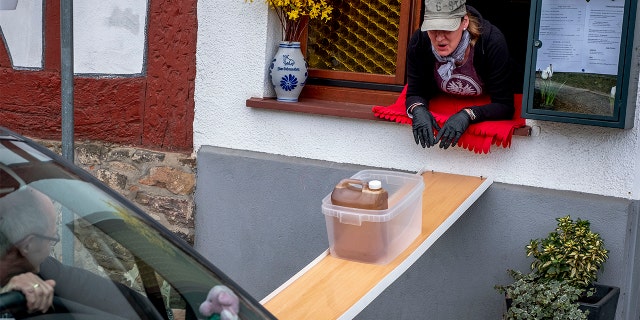 A can with apple cider slides down to car from a window of the apple cider restaurant 'Zum Lahmen Esel' in Frankfurt, Germany, Friday, April 3, 2020.(AP Photo/Michael Probst)