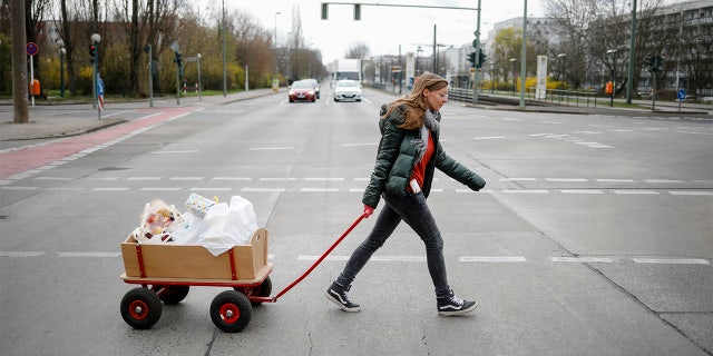 Social worker Rebekka Rauchhaus of the Christian charity the Arche, or Ark, pulls a cart as she walks through the district Hellersdorf to deliver food, toys and hygiene products to poor families in the Hellersdorf suburb of Berlin, Germany, Thursday. (AP Photo/Markus Schreiber)
