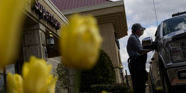 A worker delivers alcohol to a customer for curbside pickup outside a state liquor store in Fox Chapel, Pa. on April 21. (Michael Swensen/Bloomberg via Getty Images)