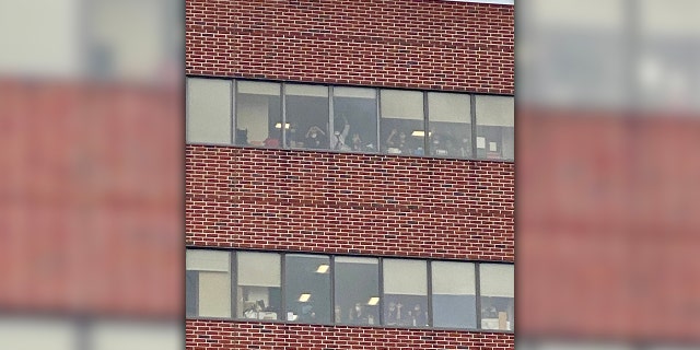 People line up at the hospital windows to get a view of a gigantic "Thank You" display outside. (Courtesy of Kyle DeLucia)<br>