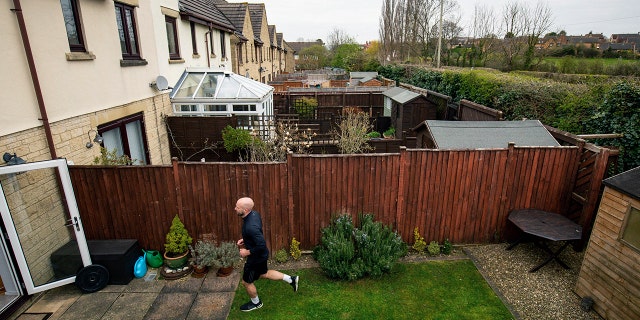 James Campbell runs a charity marathon to raise funds for the NHS, in his garden, while the country is in lockdown to control the spread of coronavirus, in Cheltenham, England, April 1, 2020. The former international athlete is spending his birthday running - in his seven-meter-long back garden - and will take over 7,000 shuttles back and forth to finish the 26.2-mile marathon. (Jacob King/PA via AP)