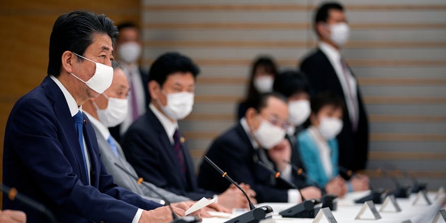 Japanese Prime Minister Shinzo Abe, left, speaks during a meeting of the headquarters for measures against the coronavirus disease at the prime minister official residence in Tokyo, Japan, Monday, April 6, 2020.