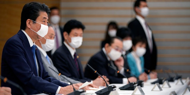 Japanese Prime Minister Shinzo Abe, left, speaks during a meeting of the headquarters for measures against the coronavirus disease at the prime minister official residence in Tokyo, Japan, Monday, April 6, 2020.