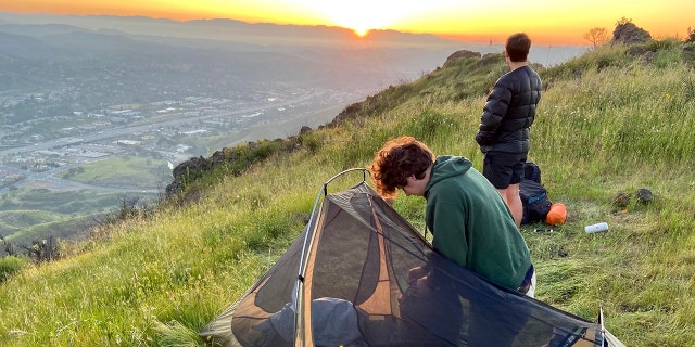 Kirk Cameron’s son James, right, stands atop a mountain overlooking Los Angeles while camping.