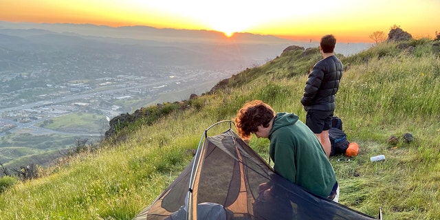 Kirk Cameron’s son James, right, stands atop a mountain overlooking Los Angeles while camping.