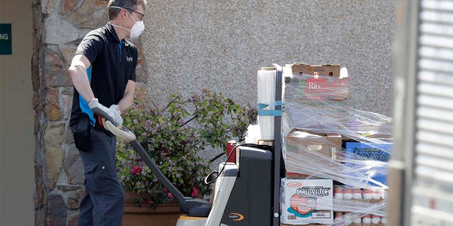 A worker wearing a mask delivers food to the Life Care Center in Kirkland, Wash. Federal authorities on Wednesday, April 1, 2020, proposed a fine of more than $600,000 for the Seattle-area nursing home connected to at least 40 deaths from the new coronavirus.