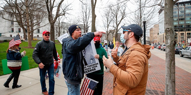 J.J. Adams (R) argues with protesters against the coronavirus shutdown in front of State Capitol in Madison, Wisconsin, on April 24, 2020. - The coronavirus pandemic soared past 50,000 in the US. (Photo by KAMIL KRZACZYNSKI / AFP) (Photo by KAMIL KRZACZYNSKI/AFP via Getty Images)
