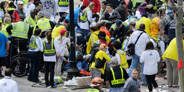 In this Monday, April 15, 2013, file photo, medical workers aid injured people at the finish line of the 2013 Boston Marathon following an explosion in Boston. (AP Photo/Charles Krupa)
