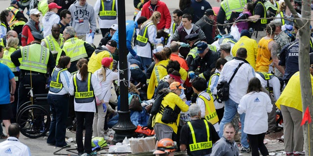 In this Monday, April 15, 2013, file photo, medical workers aid injured people at the finish line of the 2013 Boston Marathon following an explosion in Boston. (AP Photo/Charles Krupa)