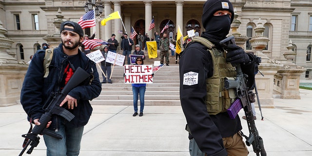 Protesters carry rifles near the steps of the Michigan State Capitol building in Lansing, Mich., Wednesday, April 15, 2020. Flag-waving, honking protesters drove past the Michigan Capitol on Wednesday to show their displeasure with Gov. Gretchen Whitmer's orders to keep people at home and businesses locked during the new coronavirus COVID-19 outbreak.