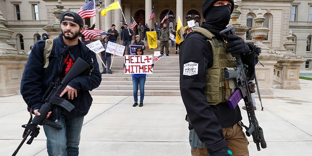 Protesters carry rifles near the steps of the Michigan State Capitol building in Lansing, Mich., Wednesday, April 15, 2020. Flag-waving, honking protesters drove past the Michigan Capitol on Wednesday to show their displeasure with Gov. Gretchen Whitmer's orders to keep people at home and businesses locked during the new coronavirus COVID-19 outbreak.