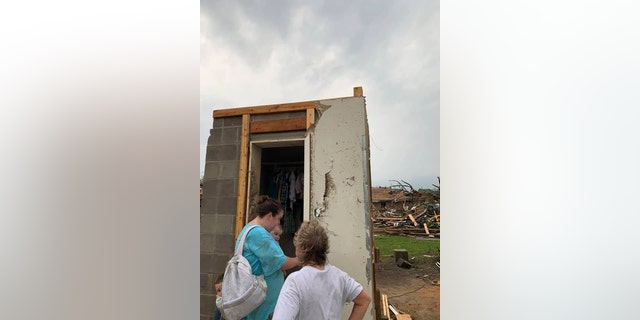 Amber Phillips stands outside the family's safe room, located on their property in Moss, Miss., following a tornado, Monday, April 13, 2020.