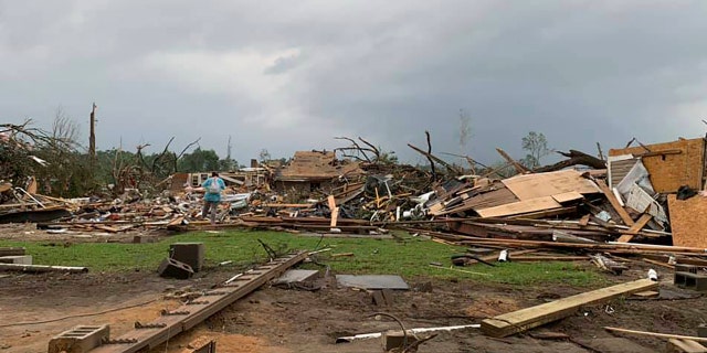 Amber Phillips surveys the damage to her family's home and meat-processing business following a tornado in Moss, Miss., Monday, April 13, 2020.