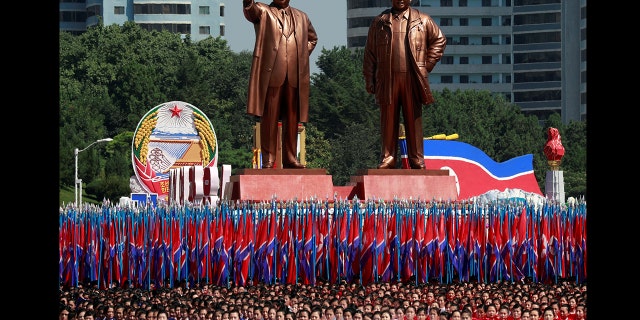 People carry flags in front of statues of North Korea founder Kim Il Sung (L) and late leader Kim Jong Il during a military parade marking the 70th anniversary of North Korea's foundation in Pyongyang. (REUTERS/Danish Siddiqui)