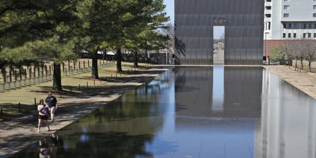 FILE - In this March 18, 2020 file photo, visitors walk next to the reflecting pool at the Oklahoma City National Memorial and Museum in Oklahoma City. The Oklahoma City National Memorial and Museum has announced that it will offer a recorded, one-hour television program in place of a live ceremony to mark 25 years after the Oklahoma City bombing due to concerns about the spread of the coronavirus. (AP Photo/Sue Ogrocki, File)