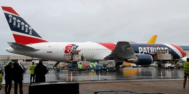 Palettes of N95 respirator masks are off-loaded from the New England Patriots football team's customized Boeing 767 jet on the tarmac, Thursday, April 2, 2020, at Logan Airport, in Boston, after returning from China. The Kraft family deployed the Patriots team plane to China to fetch more than one million masks for use by front-line health care workers to prevent the spread of the coronavirus. (AP Photo/Elise Amendola)