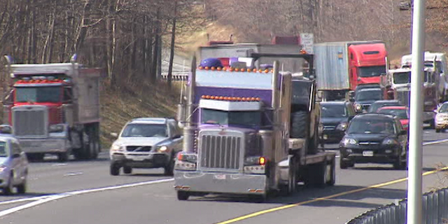 Trucks driving down highway with light traffic.