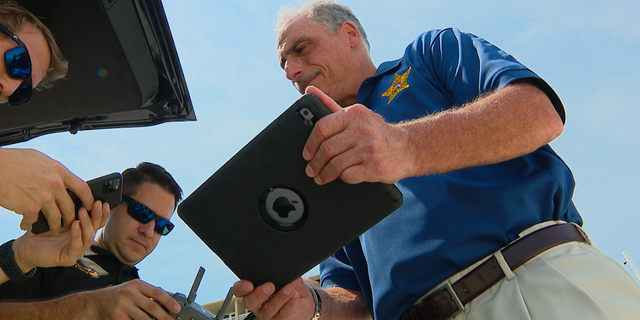 Volusia County Sheriff Mike Chitwood (right) monitors the drone with his iPad while deputies remotely pilot (Chris Pontius, Fox News)