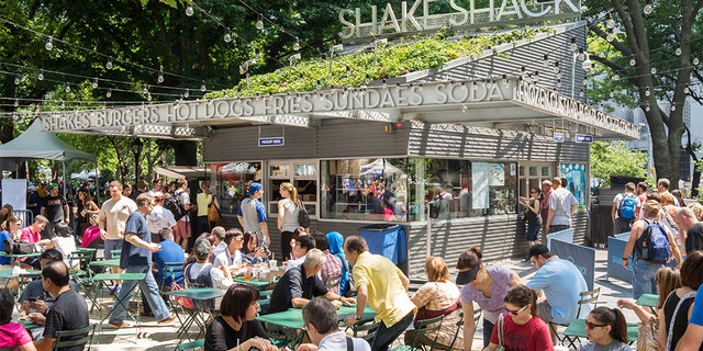 People are shown dining at the original Shake Shack in Madison Square Park in Manhattan.
