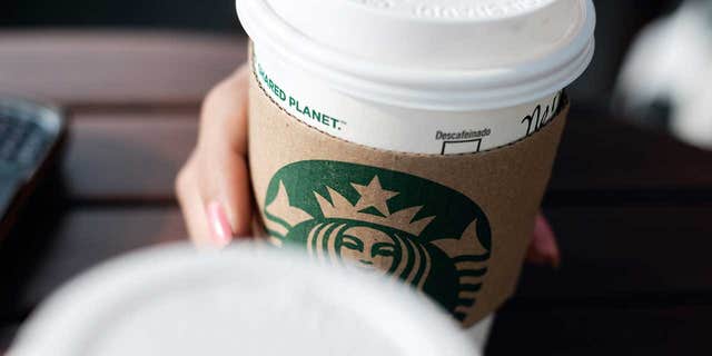 A woman holds a Starbucks coffee cup.