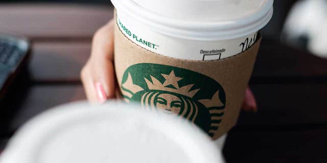 A woman holds a Starbucks coffee cup.