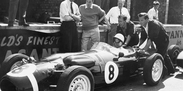 FILE - In this file photo dated July 6, 1961, Stirling Moss, at the wheel of the revolutionary new Ferguson racing car, gets a shove off from mechanics as he takes the green racer out for some practice laps at Silverstone, England. The Ferguson car, which has four-wheel drive and a new nonskid braking system, will be driven by Jack Fairman in the upcoming British Empire trophy race and Moss will drive a Cooper in the race. Stirling Moss has died at the age of 90, according to an announcement Sunday April 12, 2020, from his family. (AP Photo, FILE)