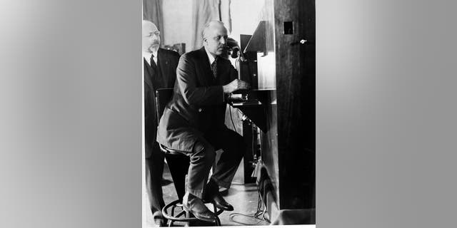 F.B. Jewett, president of A.T.&T. Co. in New York, talks with Secretary Hoover in Washington as he views Hoover's moving image in the small box at eye level. Dr. Herbert E. Ives, who is credited with the invention, looks on. (AP Photo)