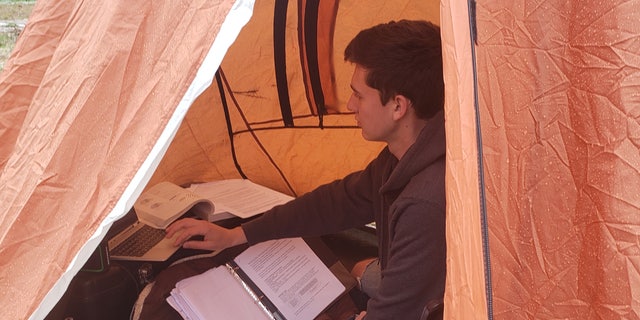 Cadet William Taylor, 18, doing his schoolwork from inside a tent outside his home in rural Pennsylvania.
