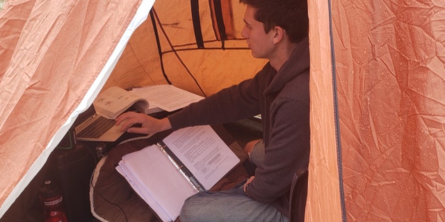 Cadet William Taylor, 18, doing his schoolwork from inside a tent outside his home in rural Pennsylvania.