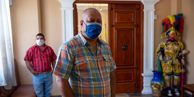 In this April 3, 2020 photo, Mayor Florencio Carrascoza Gámez, wearing a protective mask, poses for photos at his office in the largely indigenous town of Joyabaj, Guatemala, where half of the residents depend on remittances, almost all from the U.S.  (AP Photo/Moises Castillo)