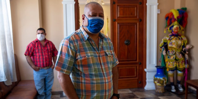 In this April 3, 2020 photo, Mayor Florencio Carrascoza Gámez, wearing a protective mask, poses for photos at his office in the largely indigenous town of Joyabaj, Guatemala, where half of the residents depend on remittances, almost all from the U.S. (AP Photo/Moises Castillo)
