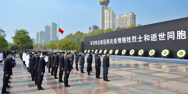 People bow their heads during a national moment of mourning for victims of coronavirus at an official ceremony in Wuhan.(AP/Chinatopix)