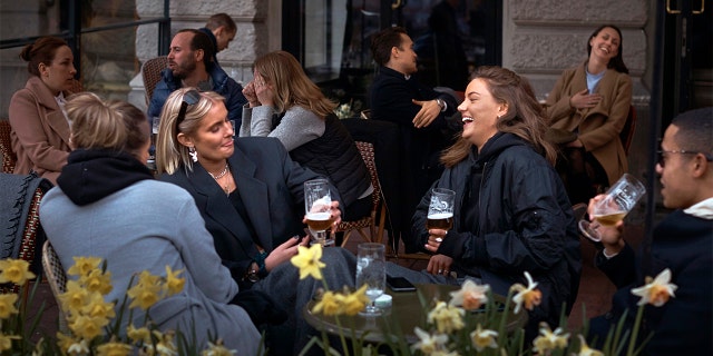 FILE - In this Wednesday, April 8, 2020 file photo people chat and drink outside a bar in Stockholm, Sweden. Sweden is pursuing relatively liberal policies to fight the coronavirus pandemic, even though there has been a sharp spike in deaths. (AP Photo/Andres Kudacki, File)