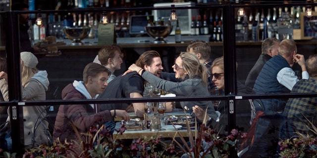 FILE - In this Saturday, April 4, 2020 file photo a couple hug and laugh as they have lunch in a restaurant in Stockholm, Sweden. (AP Photo/Andres Kudacki, File)