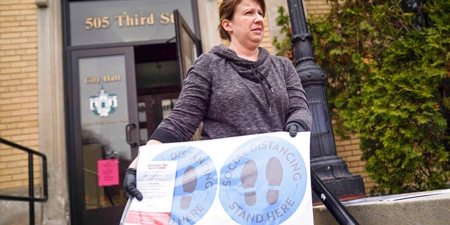 Hudson, Wis., city clerk Becky Eggen displays some of the health alert and social distancing signs. (Glen Stubbe/Star Tribune via AP)