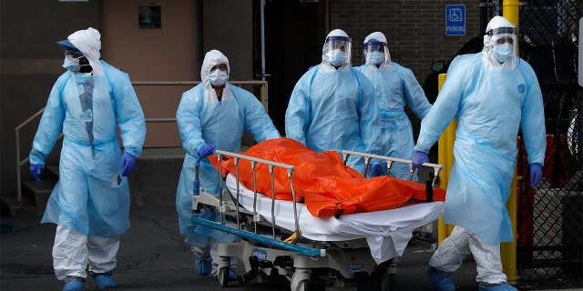 Healthcare workers wheel the body of deceased person from the Wyckoff Heights Medical Center during the outbreak of the coronavirus disease.