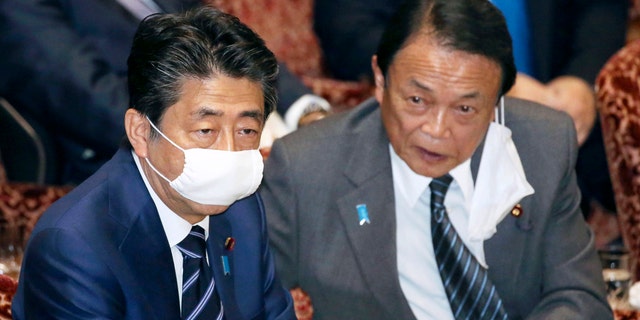 Japanese Prime Minister Shinzo Abe, left, and Financial Minister Taro Aso, wear face masks as a safety precaution against the new coronavirus attend a session of the parliament's upper house in Tokyo Wednesday.