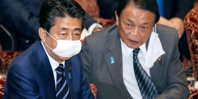 Japanese Prime Minister Shinzo Abe, left, and Financial Minister Taro Aso, wear face masks as a safety precaution against the new coronavirus attend a session of the parliament's upper house in Tokyo Wednesday.