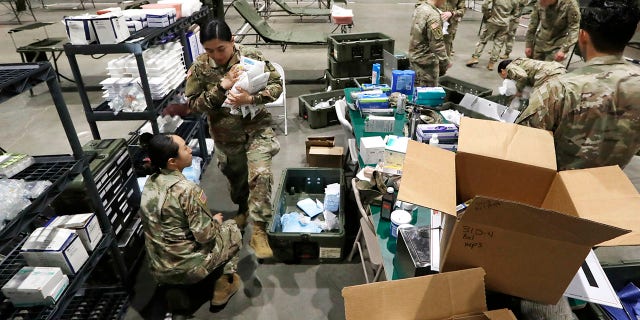 Soldiers unload supplies as they work to set up a field hospital inside CenturyLink Field Event Center on Tuesday. (AP Photo/Elaine Thompson)