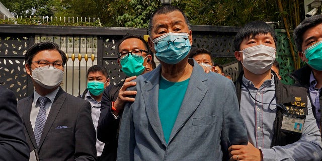 Hong Kong media tycoon Jimmy Lai, center, who founded local newspaper Apple Daily, is arrested by police officers at his home in Hong Kong, Saturday, April 18, 2020. (Associated Press)