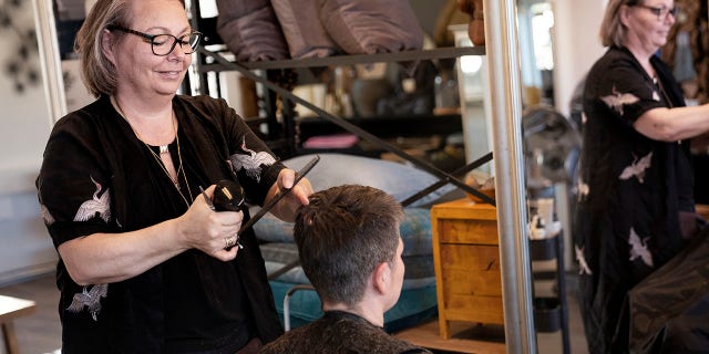 Christel Lerche cuts a customer's hair at Hot N Tot Hairdressers in Bagsvaerd on Monday after Denmark began reopening hair salons, dentists, physiotherapists, tattoo parlors and driving schools, among others that were shut down during the pandemic. (Liselotte Sabroe/Ritzau Scanpix via AP)