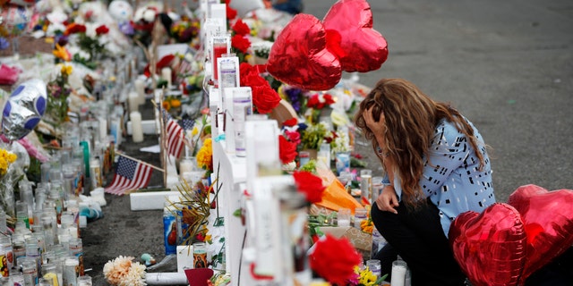 Gloria Garces kneels in front of crosses at a makeshift memorial near the scene of a mass shooting at a shopping complex in El Paso, Texas last August. (AP Photo/John Locher, File)
