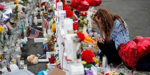 Gloria Garces kneels in front of crosses at a makeshift memorial near the scene of a mass shooting at a shopping complex in El Paso, Texas last August. (AP Photo/John Locher, File)