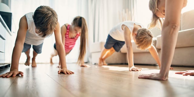 A mom is shown (at right) exercising indoors with her kids.