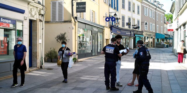 Municipal police officers check documents as they patrol in a street of Sceaux during nationwide confinement measures to counter the Covid-19. (AP Photo/Thibault Camus)