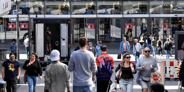 People walk to a shopping center as many smaller stores are allowed to open in Essen on Monday. (AP Photo/Martin Meissner)
